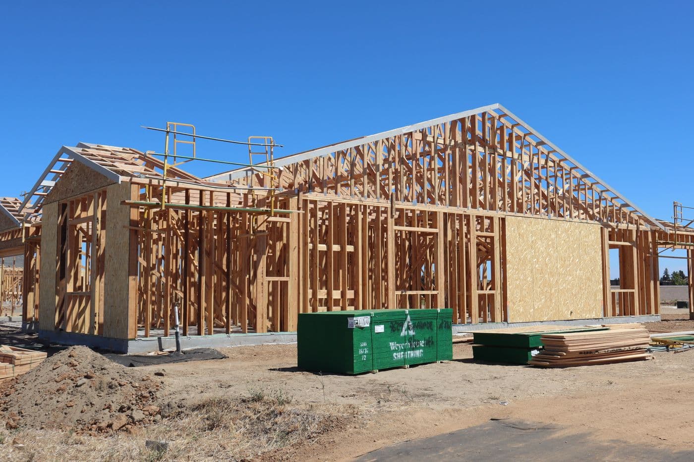 Framed custom home under construction against a clear sky